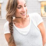 Collier charm : comment composer un bijou qui vous ressemble Femme portant un collier charm composé de plusieurs pendentifs assortis.